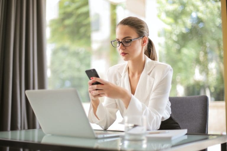 Woman holding an app in front of a laptop