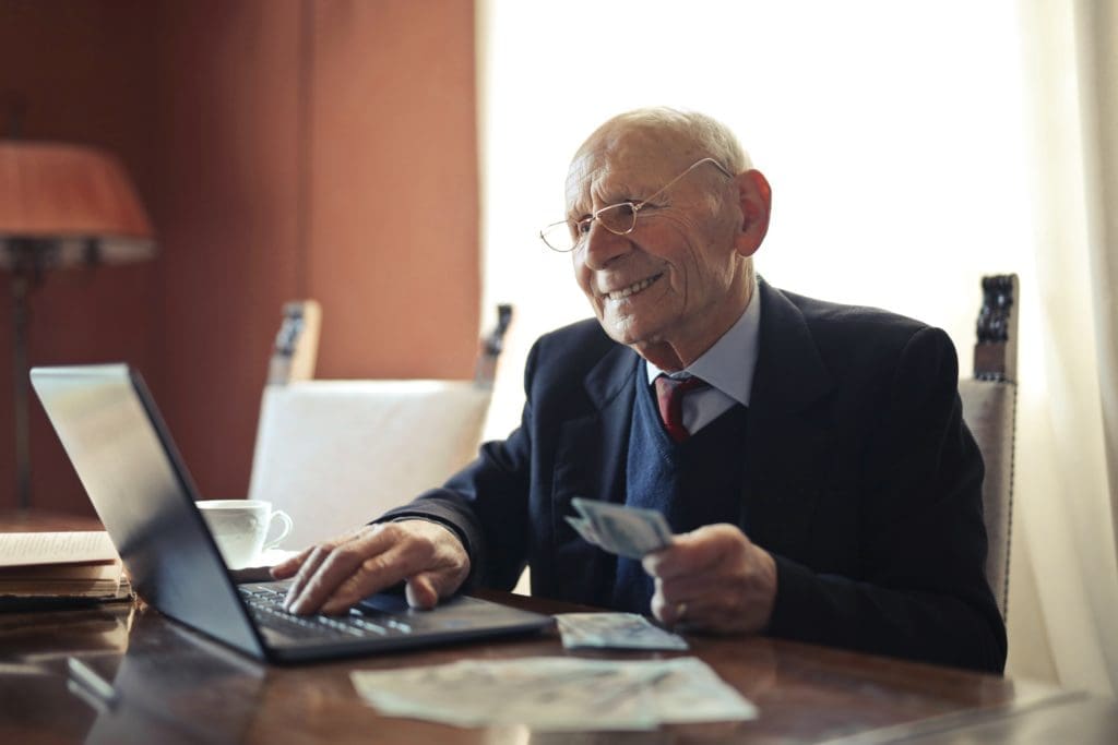 Old man checking something in front of a computer while smiling