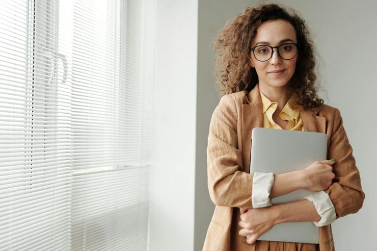 Woman smiling while hugging her laptop