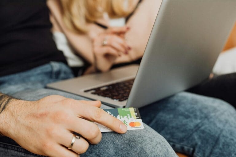 Man holding a credit card while checking his laptop