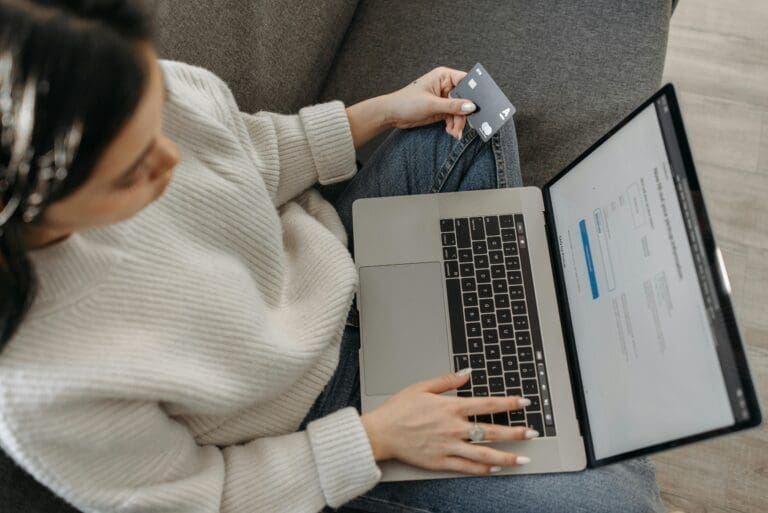 Woman holding a credit card while checking her laptop