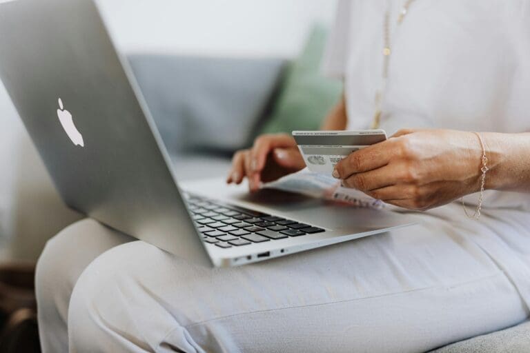 Someone holding a credit card while typing on their laptop